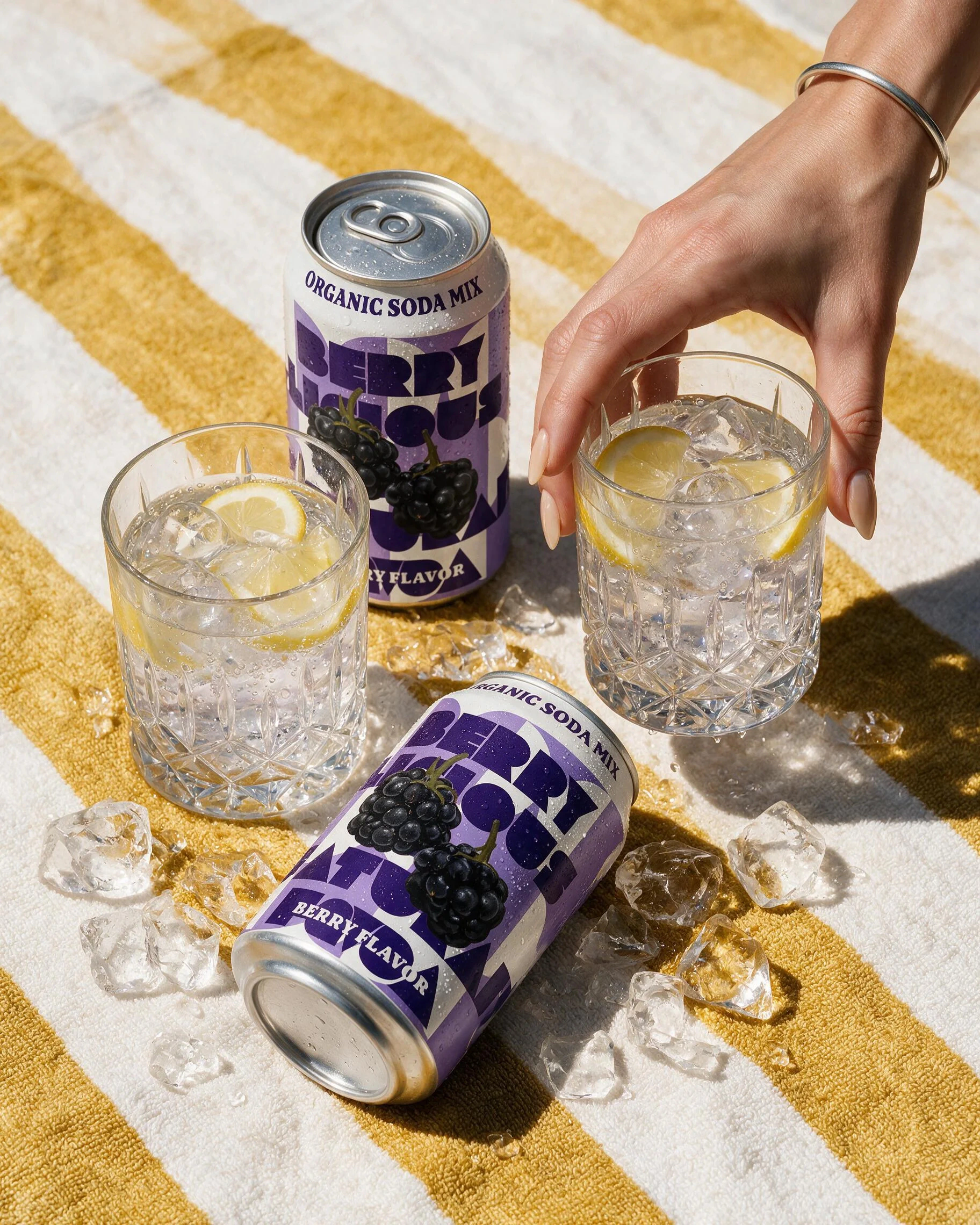 Mixed berry photoshoot: cans beside a glass of berry soda